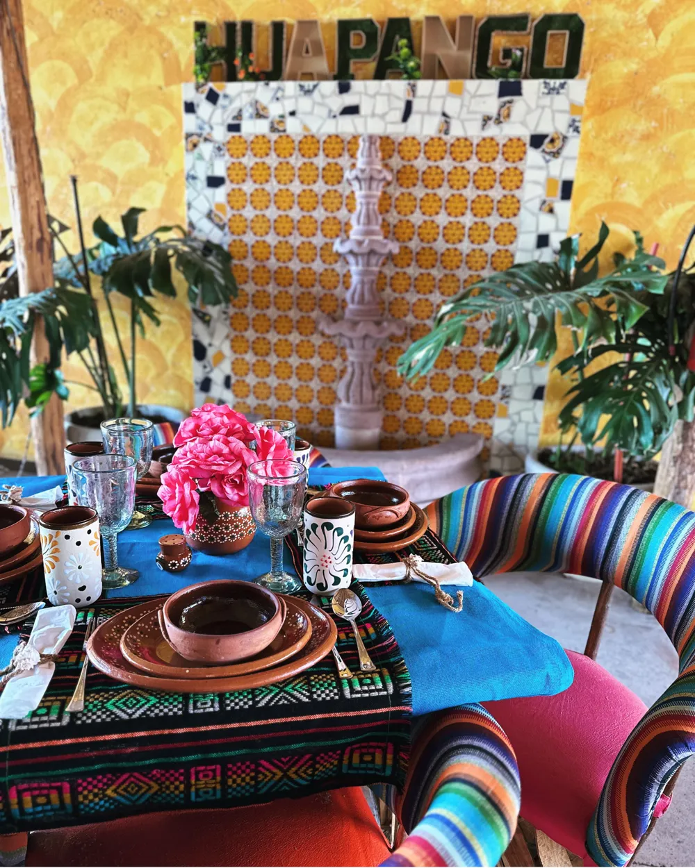 Mesa puesta con loza de barro frente a la fuente y el letrero de Huapango